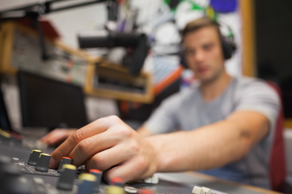 Handsome radio host moderating touching switch in studio at college